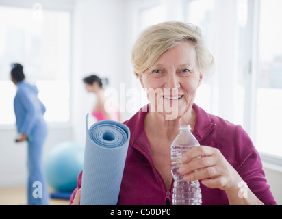 Kaukasische Frau mit Yoga Matte Trinkwasser Stockfoto