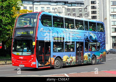 Werbung an der Seite des Doppeldeckerbusses, die den Tourismus in Malaysia mit farbenfrohen Werbespots in roter Farbe auf der Vorderseite des Busses in England UK fördert Stockfoto