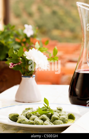 Spinat Gnocchi und Karaffe Rotwein Stockfoto