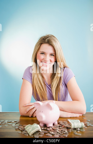 Kaukasische Teenager-Mädchen sitzend mit Münzen und Sparschwein