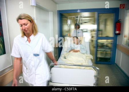 Krankenhaus. Verschieben einer Patientin in ihrem Bett aus ihr Krankenzimmer zu einem Untersuchungsraum Krankenschwestern. Stockfoto