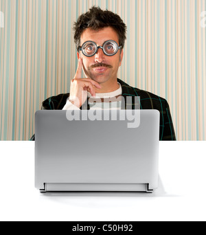 Nerd nachdenklicher Mann mit kurzsichtigen Brille und dumme Ausdruck vor einem Laptop-computer Stockfoto