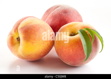 Drei reifer Pfirsich mit Blättern auf weißem Hintergrund. Stockfoto