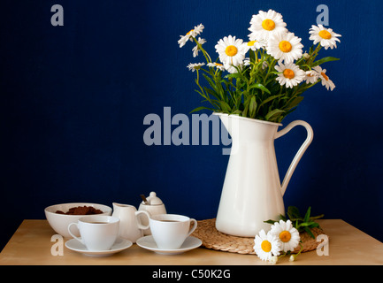 Kaffee Tassen und frischen Oxeye Gänseblümchen auf Holztisch im Innenraum Stockfoto