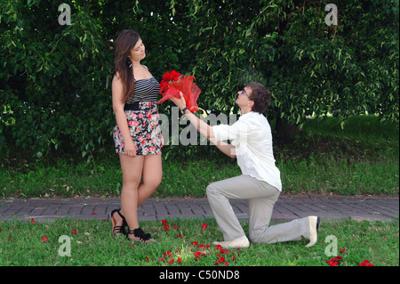 Ein junger Mann auf die Knie gibt ein Mädchen ein Dutzend Rosen und macht ein Angebot, Moskau, Russland Stockfoto