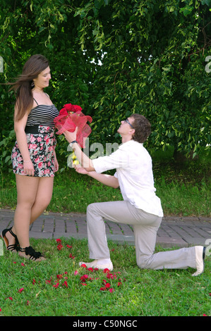 Ein junger Mann auf die Knie gibt ein Mädchen ein Dutzend Rosen und macht ein Angebot, Moskau, Russland Stockfoto