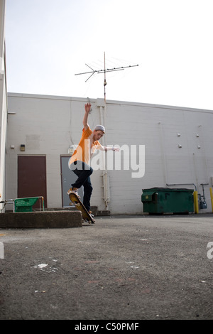 Porträt eines jungen Skateboarder einen Trick in einem städtischen Umfeld durchführen. Stockfoto