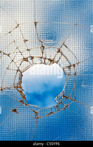 Zerbrochenes Glas - geknackt mit Loch über blauen Himmel. Stockfoto