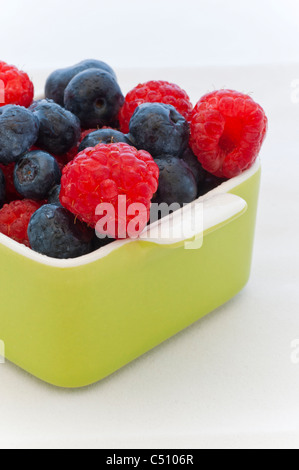 Eine Mischung aus roten Himbeeren und Heidelbeeren in kleinen Schüssel. Stockfoto