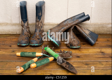 Schlammigen Stiefel und Gartengeräten auf Achterdeck nach Gartenarbeit. Stockfoto