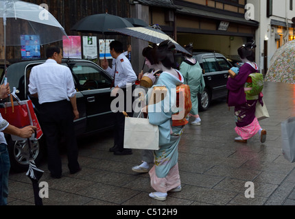 Vier japanische Maiko (Lehrling Geisha) zu Fuß zu einem Taxi im historischen Viertel Gion, Kyoto, Japan JP Stockfoto