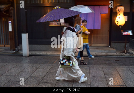 Eine japanische Geisha (Geiko) zu Fuß entlang traditionellen Restaurants im historischen Gion-Viertel, Kyoto, Japan JP Stockfoto