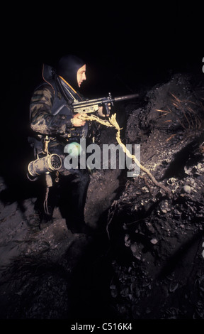 Ein Navy SEAL kreuzt am Strand in der Nacht voll bewaffnet. Stockfoto