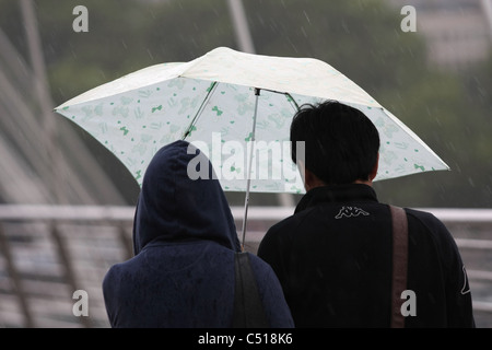 Zwei Personen einen Regenschirm in der Regen während des Gehens über die Millennium Bridge in London Stockfoto