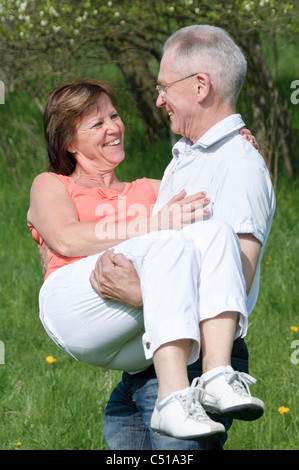 Paar mittleren Alters, Mann, eine Frau in seinen Armen trägt Stockfoto