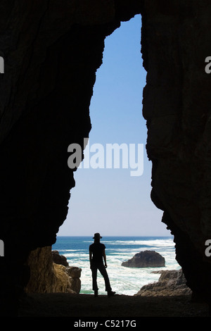 Silhouette einer Frau stehend an der Mündung einer Höhle an der Küste von Arica, Chile, Südamerika Stockfoto