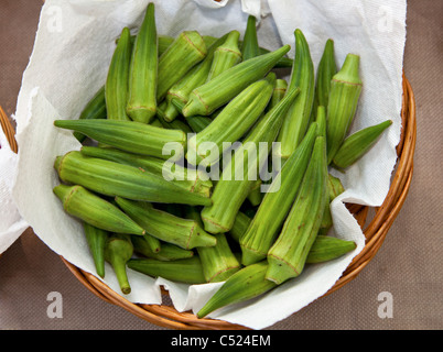 Wicker Korb mit frischen Okraschoten zum Verkauf an Open-Air Bauernmarkt Stockfoto