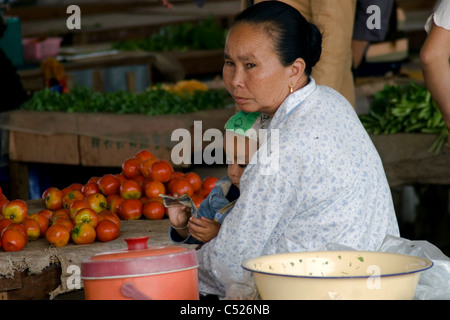 Eine Frau und ein kleiner Junge sitzen in der Nähe von einer Tabelle mit roten Tomaten einen Lebensmittelmarkt in kommunistische Laos an. Stockfoto