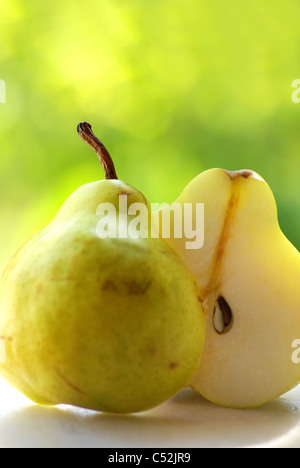 eine Birne und eine Hälfte auf grünem Hintergrund Stockfoto