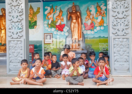 Kinder und Lehrer beten in der Weherahena Tempel von Matara, Sri Lanka, Asien Stockfoto