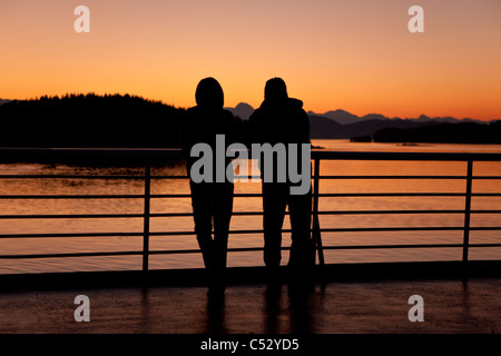 Ein paar beobachtet den Sonnenuntergang vom Deck der M/V Matanuska, wie es für Auke Bay in der Nähe von Juneau, Alaska Southeast, Herbst Köpfe Stockfoto