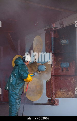 Crew-Mitglied Waschen der Propeller und der Stern der kommerziellen Fischerei in Kodiak Insel Kodiak Boatyard, Kodiak, Alaska Stockfoto