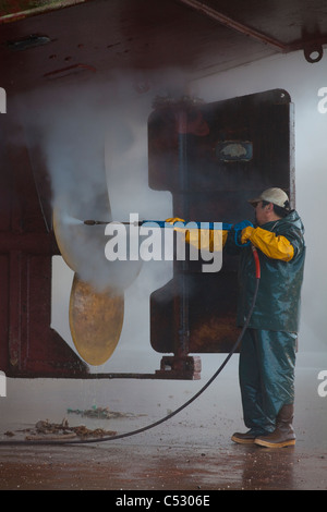 Crew-Mitglied Waschen der Propeller und der Stern der kommerziellen Fischerei in Kodiak Insel Kodiak Boatyard, Kodiak, Alaska Stockfoto