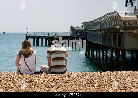 junges Paar sitzt am Strand in der Nähe von South Parade Pier essen Eis Southsea england Stockfoto