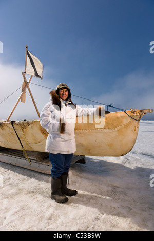 Männliche Inupiaq Eskimo Jäger steht neben einem Umiaq mit traditionellen Eskimo Parka und Dichtung Haut Hut, Tschuktschensee, Alaska Stockfoto