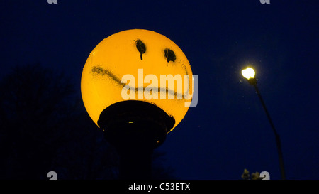 Smiley sprühte auf belisha Beacon mit Straßenlaterne im Hintergrund Stockfoto