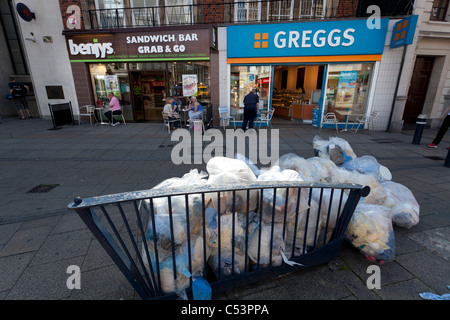 Müll-Taschen-Pfähle außen Fast-Food-Läden - Greggs und Benjys Stockfoto