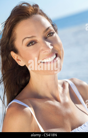 Outdoor-Porträt einer schönen junge Brünette Frau in ihren Dreißigern am Strand mit dem Meer hinter ihr getroffen Stockfoto