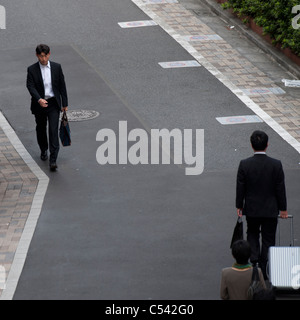 Geschäftsleute, die zu Fuß auf einem Gehweg, Tokyo, Japan Stockfoto