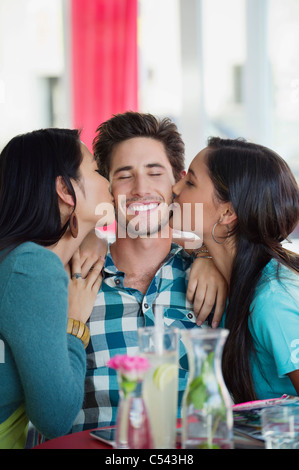 Mann wird von zwei Frauen in einem Restaurant geküsst Stockfoto