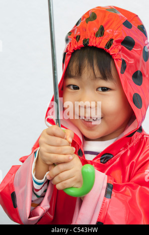 Portrait eines jungen trägt einen Regenmantel und hält einen Regenschirm, Tokyo, Japan Stockfoto