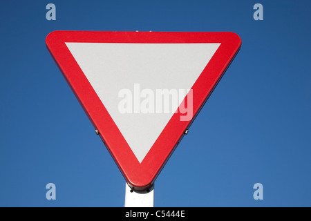 Leere Vorfahrt Zeichen gegen blauen Himmelshintergrund Stockfoto