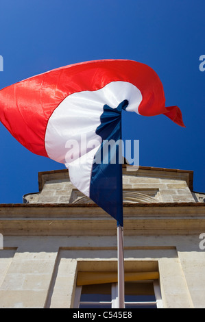Französische Flagge hing von einem alten Gebäude und fliegen vor einem strahlend blauen Himmel Stockfoto