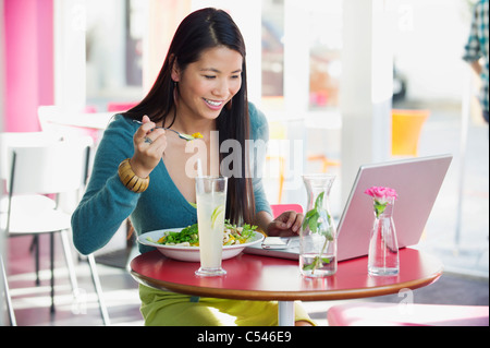 Schöne Frau, die beim Betrachten der Laptop in einem Restaurant Essen Stockfoto