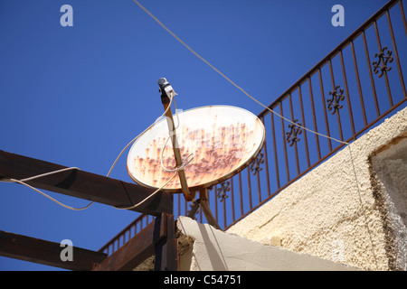 Alt und rostig Satellitenschüssel auf ein Haus mit Balkon in Griechenland Stockfoto