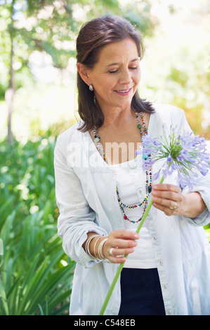 Lächelnde Frau hält eine einzelne Blume in der hand Stockfoto