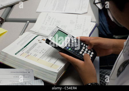 Student nutzt Grafik-Taschenrechner um zu helfen, während des Unterrichts in El Paso, Texas High School Klasse Lehrbuch Problems Stockfoto