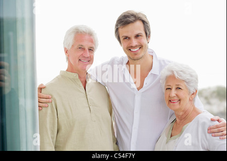 Porträt eines Mitte erwachsenen Mannes stehend mit seine Arme um seine Eltern Stockfoto