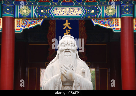 Chinesische weiße Marmorstatue eines bärtigen alten / Konfuzius / Gott vor dem Hintergrund einer kunstvollen Detail in einem Tempel. Stockfoto