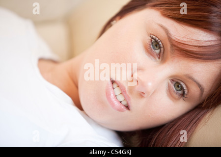 Porträt der attraktive junge Frau auf dem Sofa liegend mit entspannten Ausdruck Stockfoto