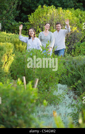 Älteres Paar gehen mit ihrer Mutter und winkenden Hand in einem Garten