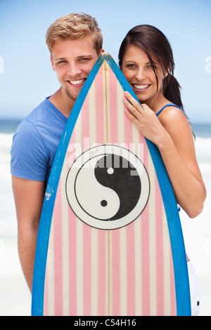 Porträt von ein paar stehen am Strand mit Surfbrett Stockfoto