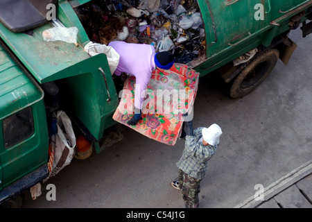 Zwei Männer sind ein Müllwagen mit Müll auf einer Stadtstraße in Mae Sai, Thailand (Sae) laden. Stockfoto