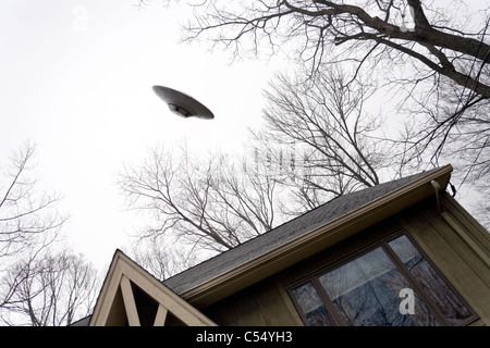 UFO fliegt über ein Haus. Stockfoto