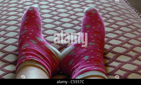 Die Füße des Kindes in roten Socken auf einen Schemel Stockfoto