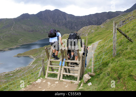 Wanderer, Klettern über hölzernen Stil auf der Strecke von Pyg, Snowdonia National Park Wales UK Stockfoto